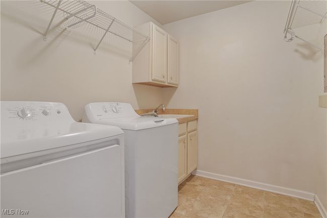 Laundry area featuring washer and dryer, cabinet space, and baseboards | Image 21