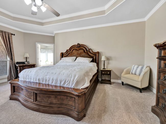 Bedroom with a tray ceiling, crown molding, a ceiling fan, carpet flooring, and baseboards | Image 22