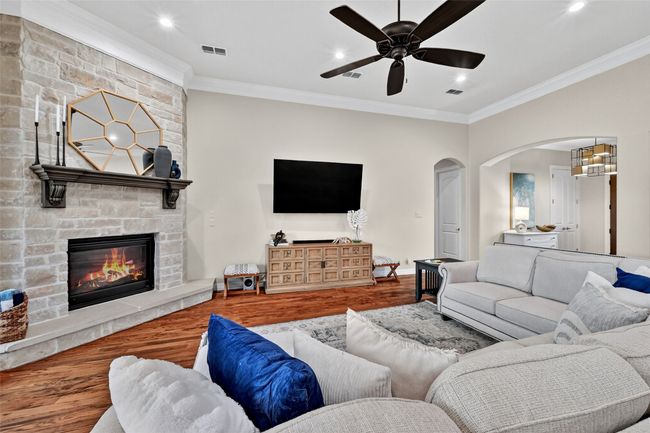 Living area featuring wood finished floors, ornamental molding, arched walkways, a ceiling fan, and recessed lighting | Image 10