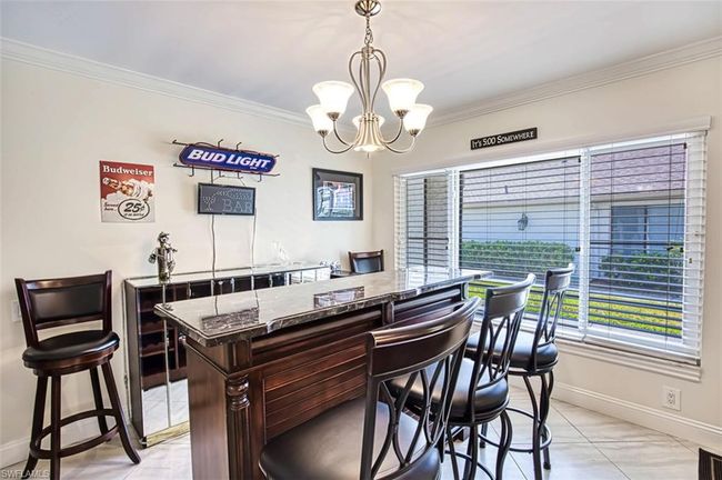 Bar with ornamental molding, a notable chandelier, and baseboards | Image 20