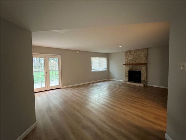 Unfurnished living room with wood finished floors, baseboards, and a fireplace | Image 11