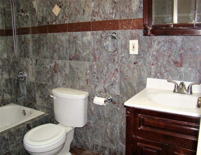 Bathroom with tile walls, vanity, and toilet | Image 11