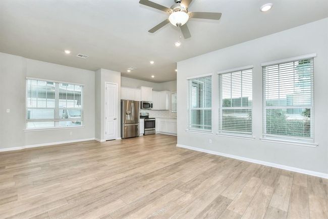 Kitchen with appliances with stainless steel finishes, light wood finished floors, white cabinets, light countertops, and tasteful backsplash | Image 6