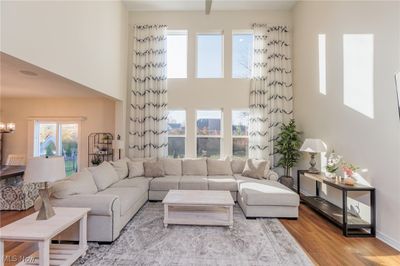 Living room with a high ceiling, light hardwood / wood-style flooring, and an inviting chandelier | Image 3