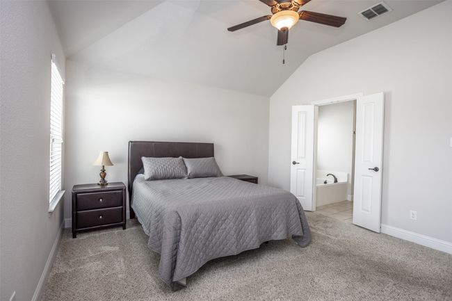 Carpeted master bedroom with lofted ceiling, ensuite bathroom, and ceiling fan | Image 23