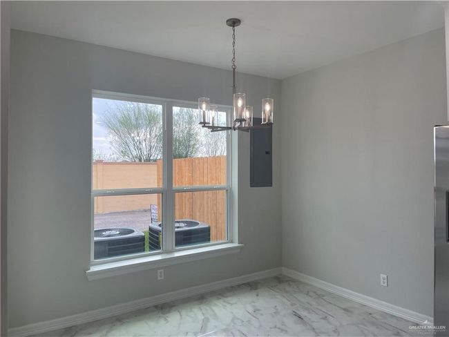 Unfurnished dining area with marble look tile flooring, a chandelier, electric panel, and baseboards | Image 6