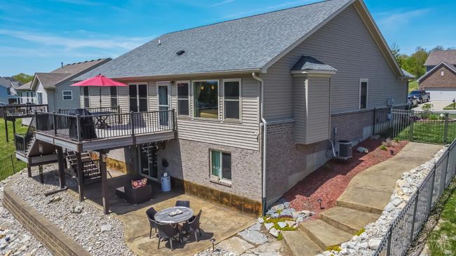 Aerial view of the rear elevation. Tiered, two-tone composite deck system (rails, gutter, patio ceiling, stairs). Stamped, embossed patio (31'x10'+) with adjoining 5' wide walk paths on both sides of the house. 5' tall aluminum fence with locking gates. | Image 8