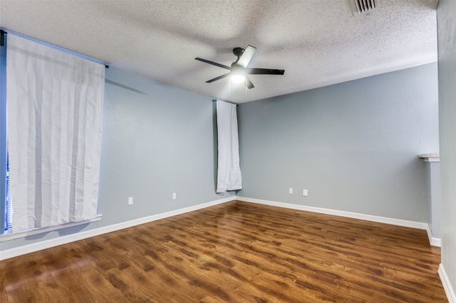Empty room with wood finished floors, a textured ceiling, and a ceiling fan | Image 16