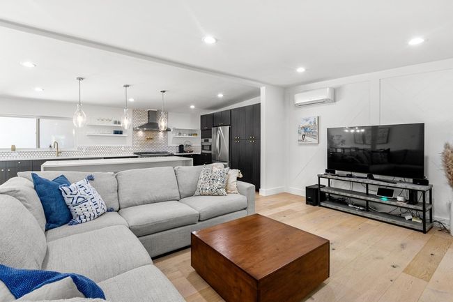 Living room featuring light wood finished floors, a wall mounted air conditioner, and recessed lighting | Image 14