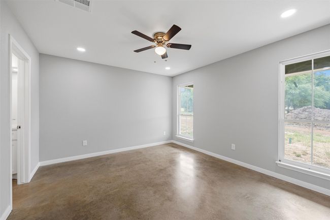 Empty room with finished concrete flooring, visible vents, a healthy amount of sunlight, and baseboards | Image 10