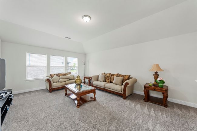 Carpeted living room with baseboards and lofted ceiling | Image 31