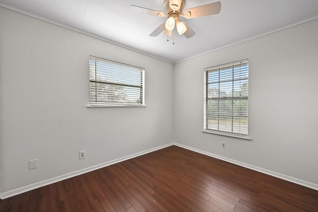 Unfurnished room featuring wood finished floors, baseboards, a ceiling fan, and ornamental molding | Image 12