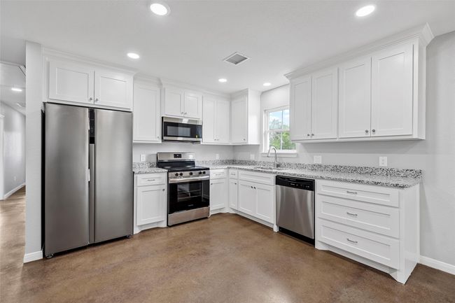 Kitchen with a sink, concrete floors, visible vents, baseboards, and appliances with stainless steel finishes | Image 4