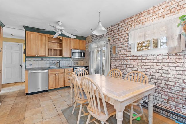 Kitchen featuring open shelves, stainless steel appliances, a sink, brick wall, and a wealth of natural light | Image 4