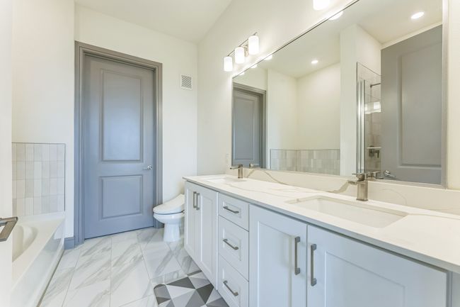 Full bathroom featuring double vanity, a garden tub, and marble look tiles | Image 19