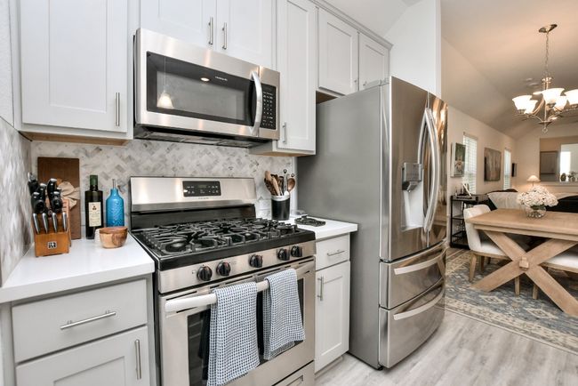 Kitchen featuring light countertops, stainless steel appliances, open floor plan, decorative backsplash, and a notable chandelier | Image 16