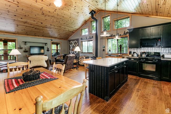 Kitchen with black appliances, dark cabinetry, open floor plan, wood ceiling, and wood-type flooring | Image 15