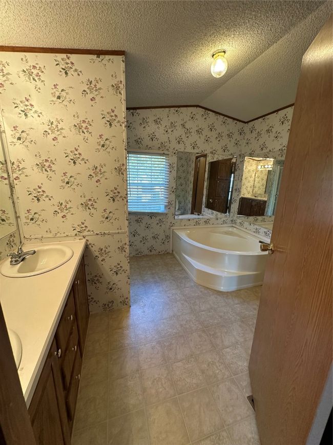 Bathroom featuring wallpapered walls, ceiling, a bath, and double vanity | Image 21