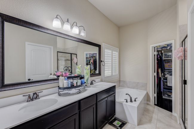 Bathroom with a stall shower, a bath, a walk in closet, double vanity, and tile patterned floors | Image 25