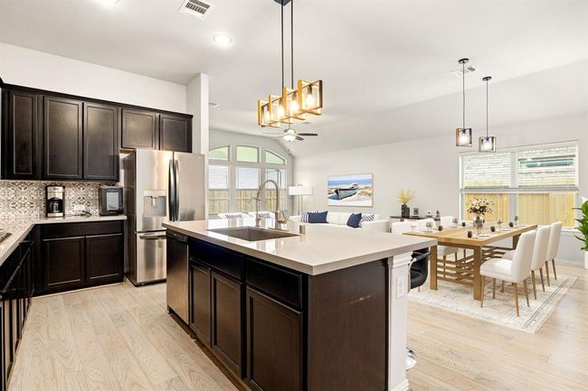 This stunning kitchen displays such a beautiful contrast with the dark stained cabinets, custom neutral paint, granite countertops, light modern backsplash, and SS appliances, oversized kitchen island with extra storage, breakfast bar, recessed lighting, high ceilings and walk in pantry. *Virtually Staged | Image 8
