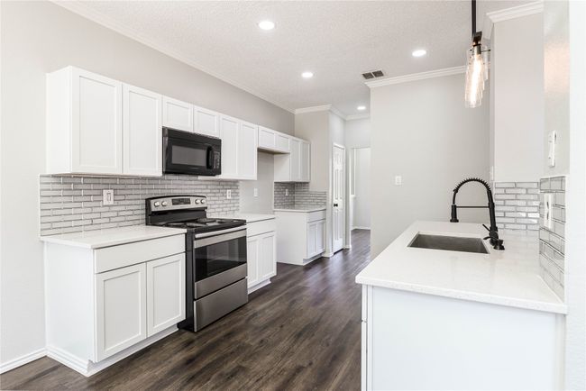 Kitchen with black microwave, stainless steel electric range oven, a sink, decorative backsplash, and recessed lighting | Image 8