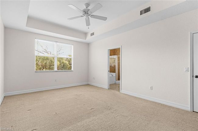 Unfurnished room with light colored carpet, ceiling fan, and a raised ceiling | Image 22