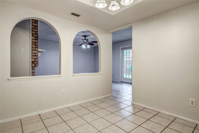 Empty room featuring light tile patterned flooring, baseboards, a ceiling fan, and a chandelier | Image 16