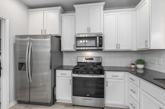 Kitchen featuring stainless steel appliances, backsplash, dark countertops, and white cabinetry | Image 10