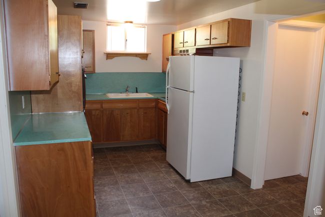 Kitchen with freestanding refrigerator, light countertops, and brown cabinetry | Image 16