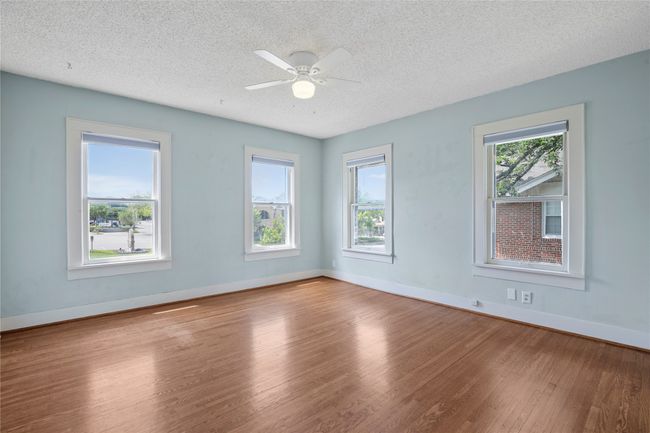 Spare room with wood finished floors, a textured ceiling, baseboards, and ceiling fan | Image 15