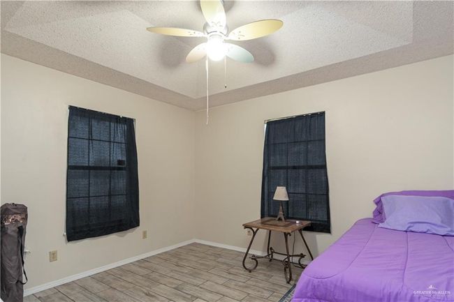 Bedroom with light wood-style floors, baseboards, a textured ceiling, and a ceiling fan | Image 13