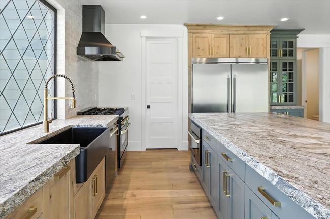 Kitchen featuring wall chimney exhaust hood, high end appliances, light wood-style flooring, recessed lighting, and light stone counters | Image 15