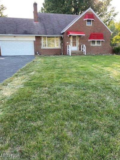 View of front facade featuring a front yard and a garage | Image 1