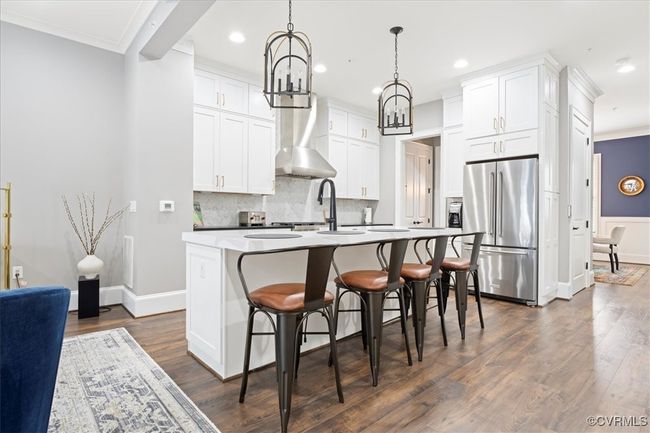 Kitchen with white cabinets, a kitchen island with sink, backsplash, dark wood-style floors, and freestanding refrigerator | Image 13