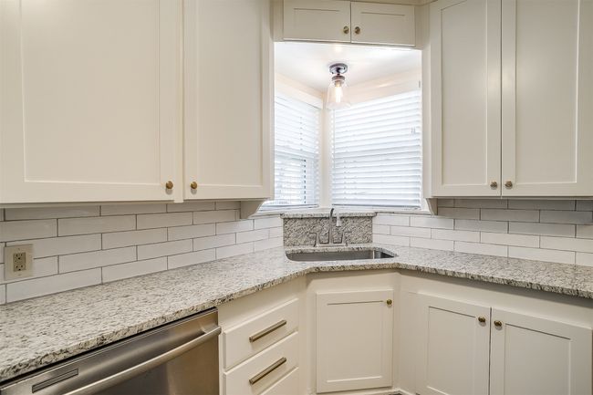 Kitchen featuring dishwasher, backsplash, white cabinetry, and light stone counters | Image 9