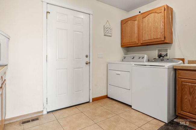 Laundry room featuring cabinets, sink, washing machine and dryer hookups, tiled floors & door out to front of the home | Image 18