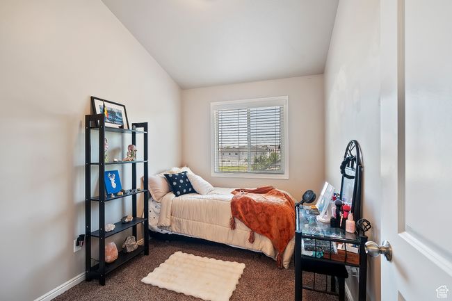 Bedroom with dark colored carpet and lofted ceiling | Image 20