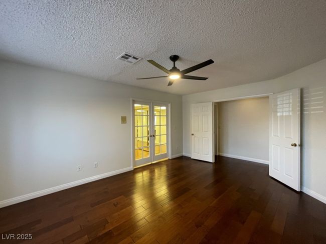 Unfurnished room with a textured ceiling, a ceiling fan, dark wood-type flooring, and french doors | Image 28