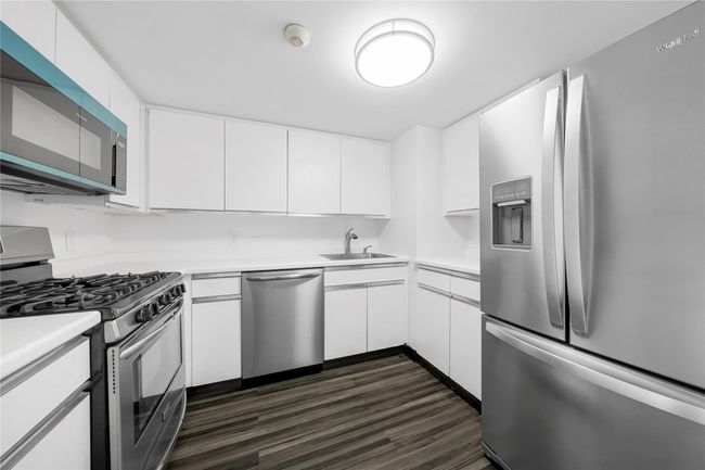 Kitchen featuring appliances with stainless steel finishes, a sink, white cabinetry, and light countertops | Image 11