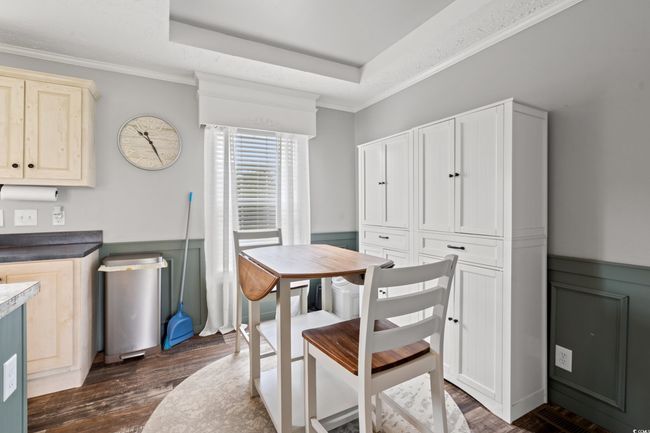 Dining space with dark wood finished floors, wainscoting, crown molding, and a raised ceiling | Image 9