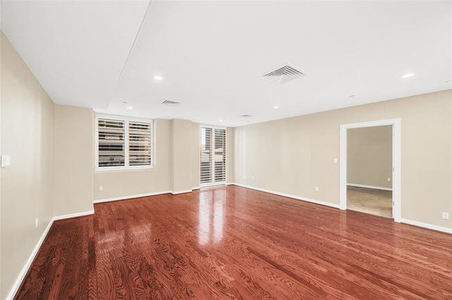The Living Room is approximately 22'x18'* allowing for large furniture pieces and flexibility in furniture arrangement. All windows in home have plantation shutters. Open doorway leads into Primary Suite. Recessed lighting overhead. *Buyer to verify dimensions. | Image 14
