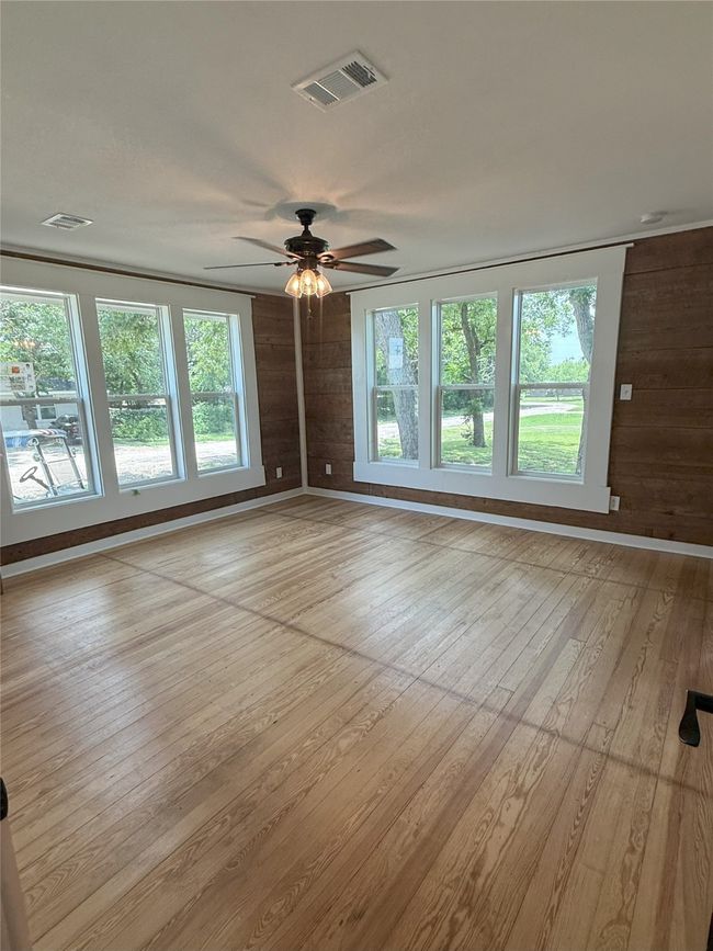 Spare room with light wood-style flooring, ceiling fan, plenty of natural light, and wood walls | Image 19
