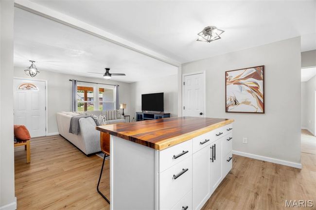 Kitchen with wood counters, light wood-type flooring, open floor plan, white cabinets, and a kitchen bar | Image 13