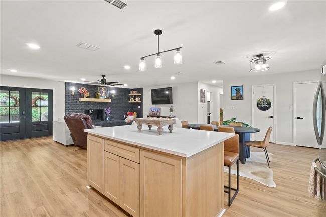 Kitchen with light brown cabinets, a ceiling fan, light wood finished floors, open floor plan, and a center island | Image 13
