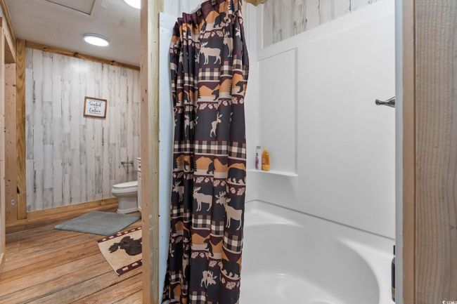 Bathroom with wood finished floors, wooden walls, and shower / bath combo with shower curtain | Image 14