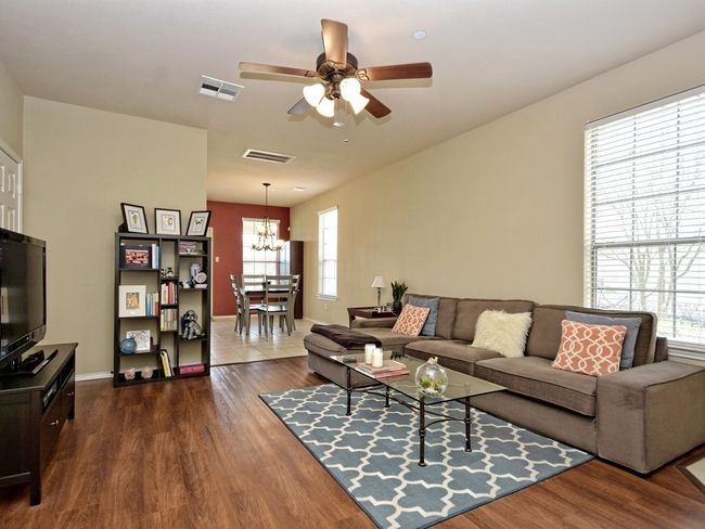 Living room with dark wood finished floors, baseboards, and ceiling fan with notable chandelier | Image 6