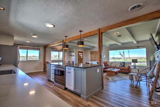 Kitchen featuring electric stove, open floor plan, wood finished floors, a textured ceiling, and freestanding refrigerator | Image 14