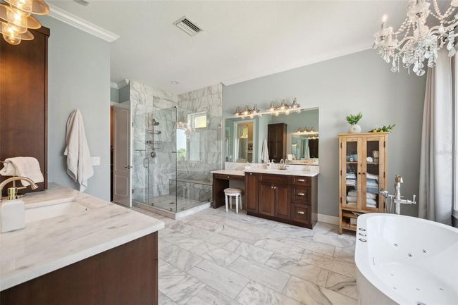 Luxurious master bathroom surrounded by real marble, jetted self-standing tub and his and her vanities. An oversized shower with bench seat completes this spacious and airy spa-like retreat! (also with wide open water view to the right from tub). | Image 48