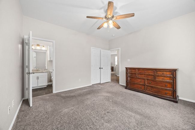 Unfurnished bedroom with carpet flooring, ceiling fan, a closet, baseboards, and ensuite bath | Image 23