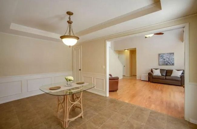 Dining space with a raised ceiling, a decorative wall, a wainscoted wall, and ornamental molding | Image 6